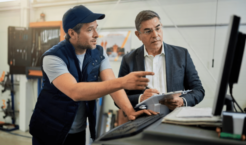 Imagem do artigo Ideias para eficência operacional para empresas | Apresenta dois homens conversando em um ambiente corporativo da indústria